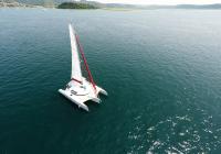 white trimaran yacht charter crew in turquoise t-shirt at blue sea